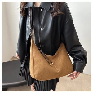 Detail of brown suede hobo bag featuring white contrast stitching and long fringe tassel