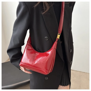 Red glossy patent leather crescent hobo shoulder bag styled with a black suit and skirt