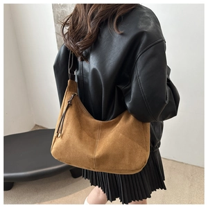 Détail d'un grand sac hobo en daim marron avec cordon de serrage porté par mannequin