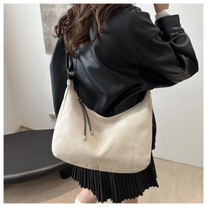 Vue détaillée d'un sac hobo en daim crème avec bandoulière marron et pompons décoratifs