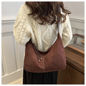 Close-up of brown suede hobo bag with fringe details on model in cream sweater