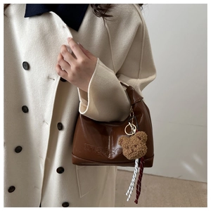 Detail of brown PU leather tote bag with Maison embossing and plush bear charm