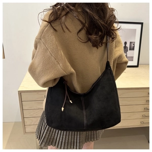 Retro black matte hobo bag with white stitching and gold pendant shown on model