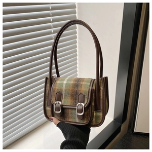 Dettaglio del tessuto in lana a quadri verdi e cinturini in pelle di una borsa vintage