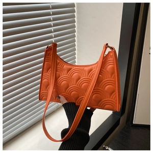 Detail showing bright orange crescent bag with 3D wave embossing and slender handle