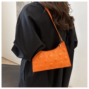 Detail of bright orange crescent bag with fan-shaped quilting on black coat backdrop