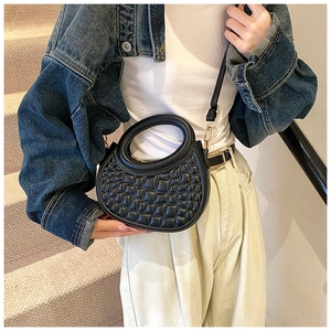 Detail of black semi-circular PU leather bag with embossed grid texture and gold zipper