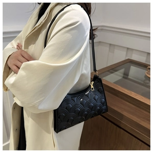 Close-up of a black quilted shoulder bag with wave texture and glossy leather finish