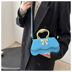 Fashionable light blue handbag with golden bow detail and unique metallic top handle