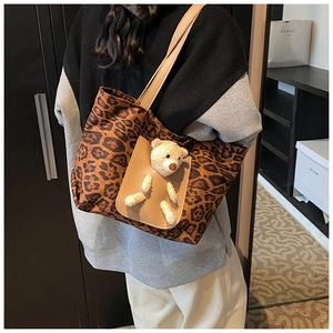 Detail of leopard print canvas tote bag featuring a leather pocket and plush bear charm