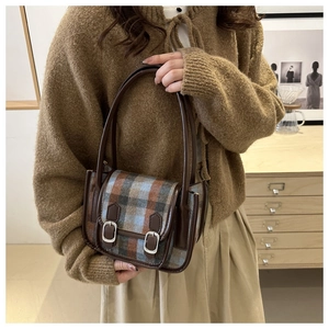 Dettaglio della borsa a quadri in lana con finiture in pelle marrone indossata da una donna