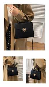 Detail of a black trapezoid faux leather handbag featuring a golden flower-shaped buckle