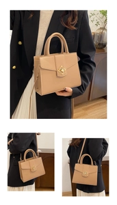Detailed view of the gold floral metallic clasp on a minimalist beige leather handbag