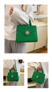 Detail of green faux leather handbag featuring a golden floral lock and top handle