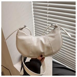 Detail of creamy white crescent shoulder bag with crinkled texture and silver metal zipper