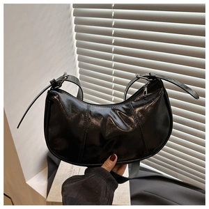 Detail of black glossy leather crescent bag with silver zipper and adjustable strap