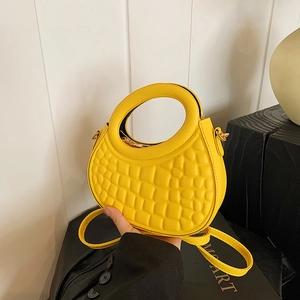 Detail of yellow round-handle handbag featuring embossed pebble texture and gold zipper