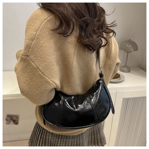 Detailed view of the sleek black crescent shoulder bag in glossy faux leather material
