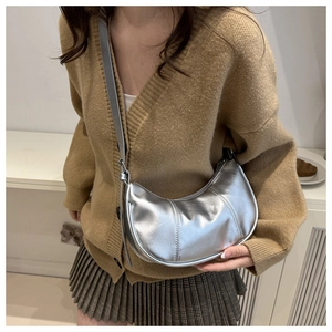 Close-up of a silver crescent underarm bag with glossy metallic finish and pleated details