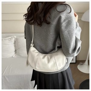 Detail of white textured crescent shoulder bag with three-panel stitching and adjustable strap
