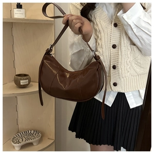 Macro detail of brown patent leather crescent bag with smooth zipper and stitching