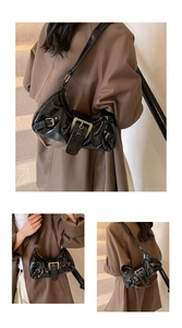 Detail view of the black glossy underarm bag with bold silver metal buckle and belt straps