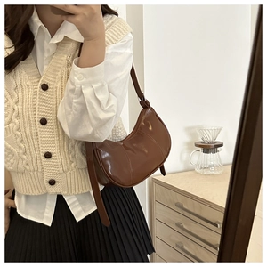 Brown leather crescent shoulder bag shown in a stylish mirror selfie with a retro vibe
