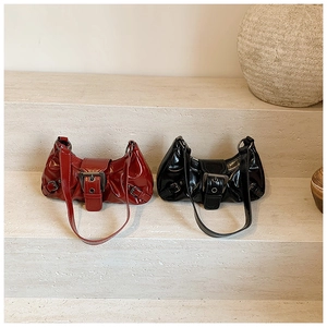 Detail of glossy black and deep red crescent shoulder bags with vintage buckle accents
