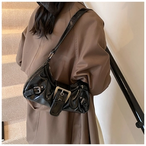 Side view of black glossy patent leather shoulder bag with vintage silver metal buckles
