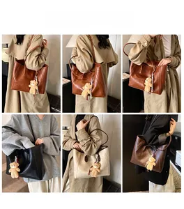 Detail view of large leather tote bag with plush bear charm and spacious compartment