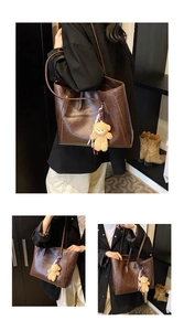Detail view of brown vintage tote bag featuring faux leather texture and plush bear charm