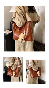 Close-up of vintage brown leather tote bag with cute plush bear charm and long shoulder straps