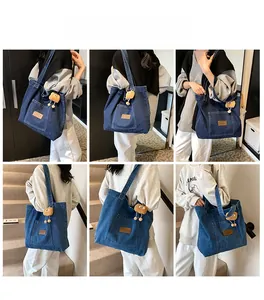 Detail of blue denim tote bag with brown leather patch and orange plush charm accessory