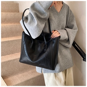 Detail of minimalist black large tote bag in matte synthetic leather on model
