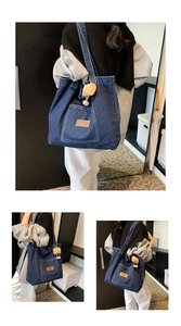 Detail of blue denim tote bag with front pocket and yellow cartoon plush pendant charm