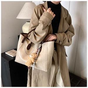 Minimalist beige tote bag with dark brown handles and cute plush bear charm on side