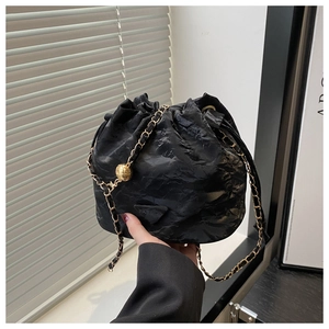 Detail of black pleated bucket bag with gold chain strap and adjustable metal sphere