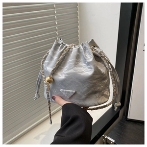 Detail of silver pleated bucket bag with gold chain strap and metal ball charm
