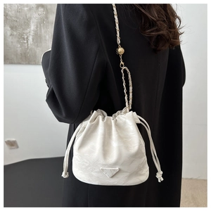 Detail of white leather drawstring bucket bag with gold chain strap and metal ball buckle