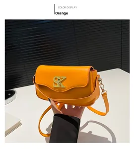 Detail einer orangefarbenen Ledertasche mit goldenem SK-Verschluss und schmalem Gurt