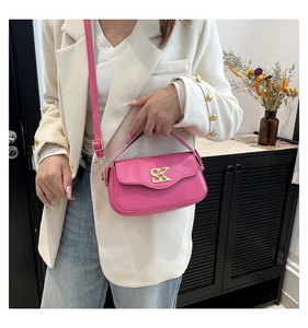 Detail der rose-pinkfarbenen Umhängetasche mit goldenem SK-Metalllogo auf hellem Blazer