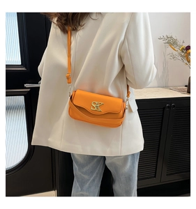 Detail der orangefarbenen Ledertasche mit einer markanten goldenen SK-Metallschnalle