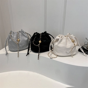 Three minimalist drawstring bucket bags with chain straps in silver, black, and white