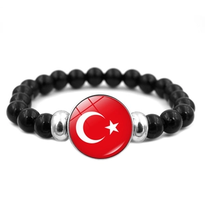 Détail d'un bracelet en perles noires avec charm drapeau Turquie et perles argentées