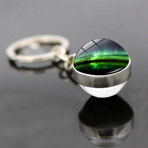 Vue macro du porte-clés en verre double face avec motif d'aurore boréale verte éclatante