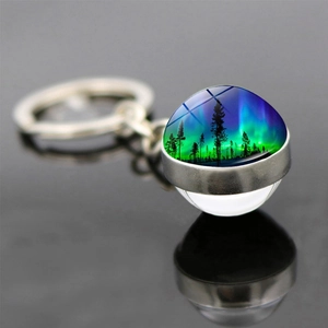 Vue macro d'un porte-clés pendentif en verre double face avec aurore et forêt