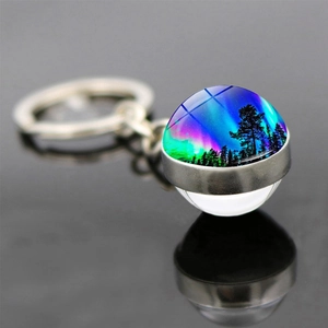 Détail macro du porte-clés boule de verre aurore boréale avec reflet de forêt noire