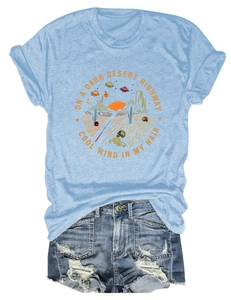 Dettaglio della stampa desertica retrò su t-shirt azzurra e shorts in denim strappati