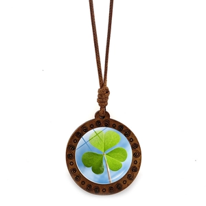 Detailed view of a round wood pendant necklace with lucky green clover under glass