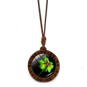 Detailed close-up of a round wood pendant necklace with a green four-leaf clover